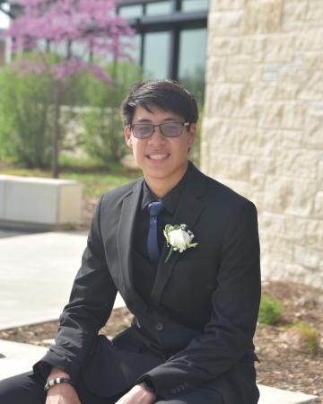 A man in a dark suit sitting outside