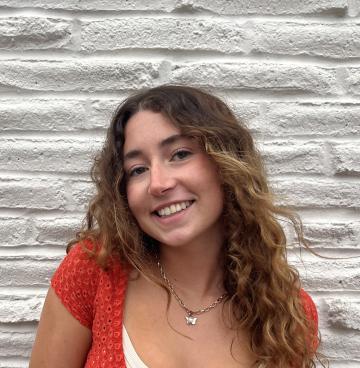 A woman smiling standing in front of a gray rock wall