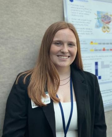 A woman in a black blazer in front of a scientific poster