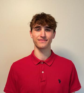 A man in a red shirt in front of a white wall